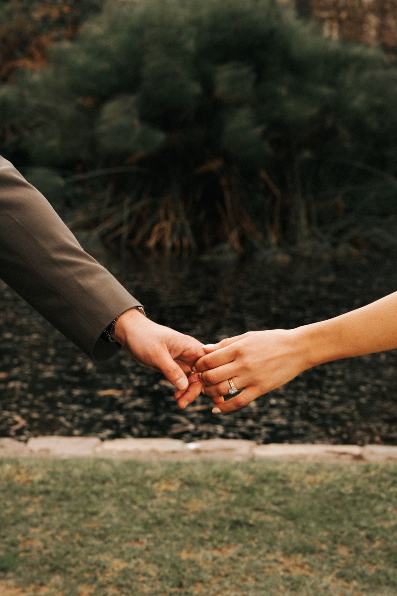 Close up of two hands reaching for each other above a lawn