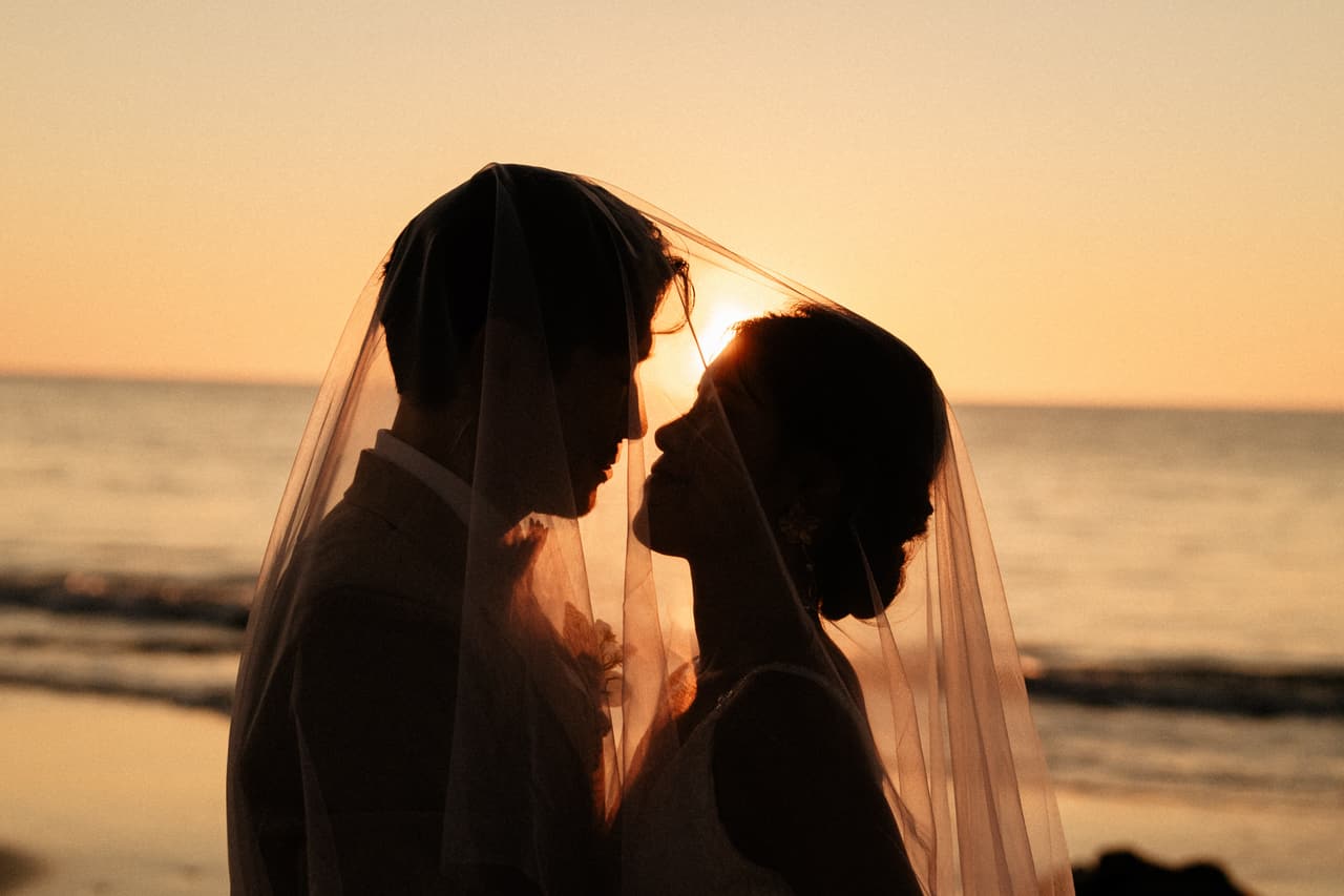 Close silhouette of a couple under a veil against the sunset over the sea