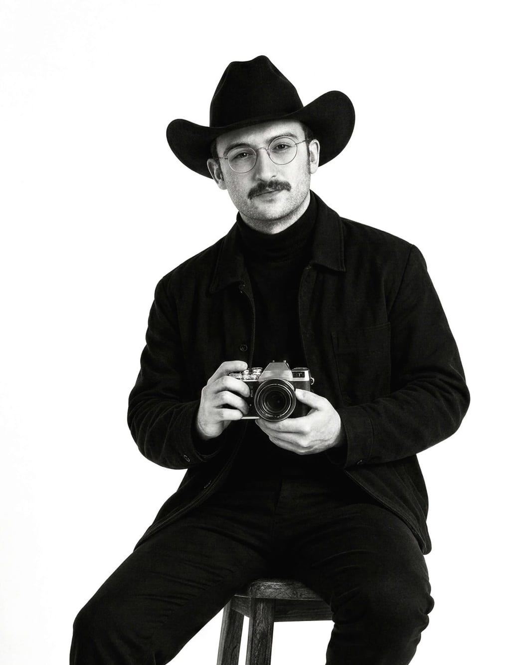 Jay, founder of Jay Chubby Wedding, sitting on a stool with a camera
