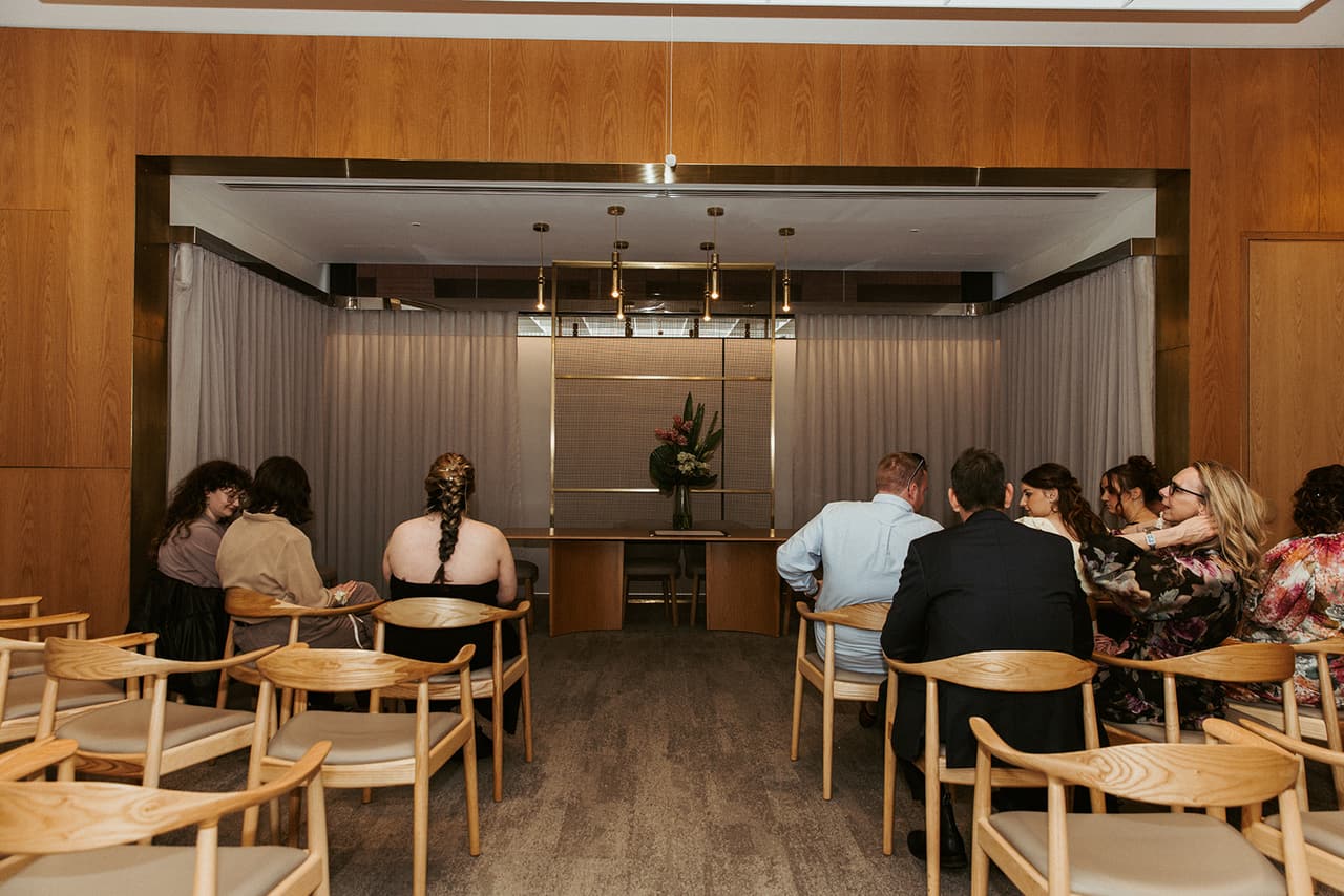 Guests seated in the marriage room before the ceremony, facing the curtained alcove and its long table