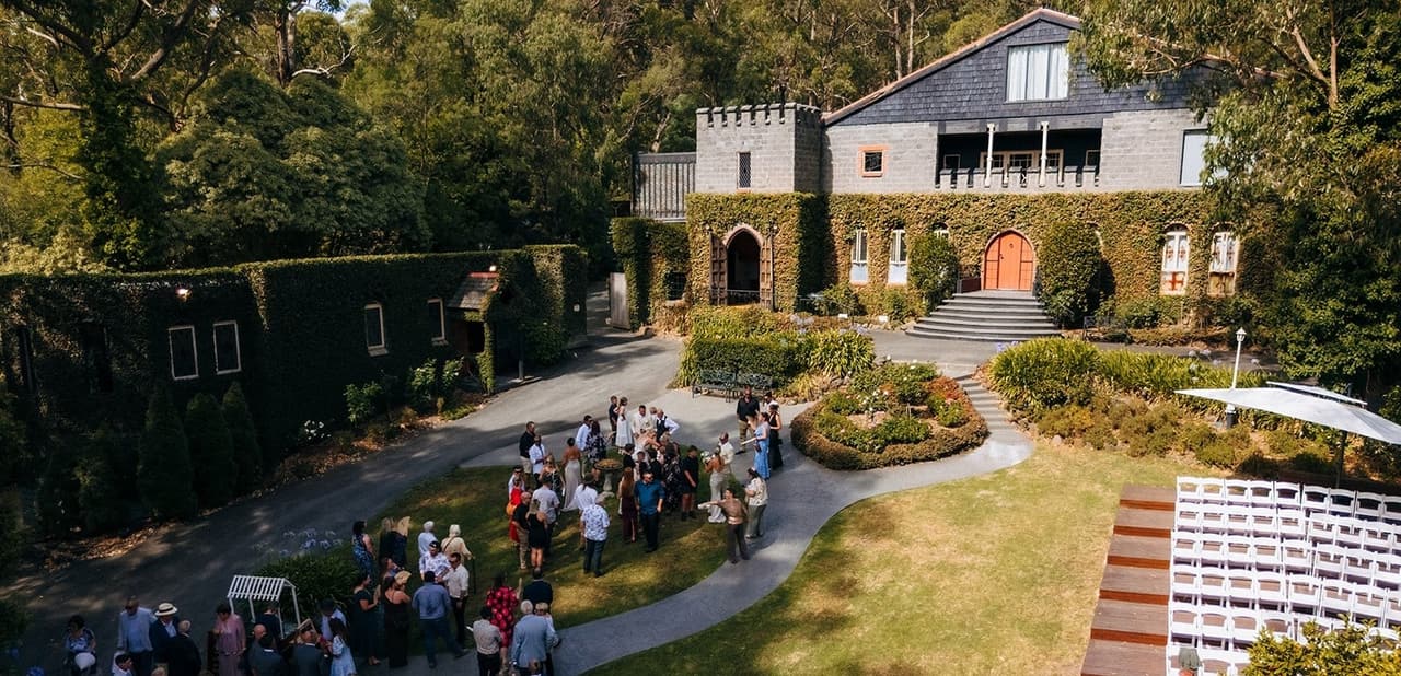 The castle, its lawns and the ceremony deck from above, guests gathered by the gardens
