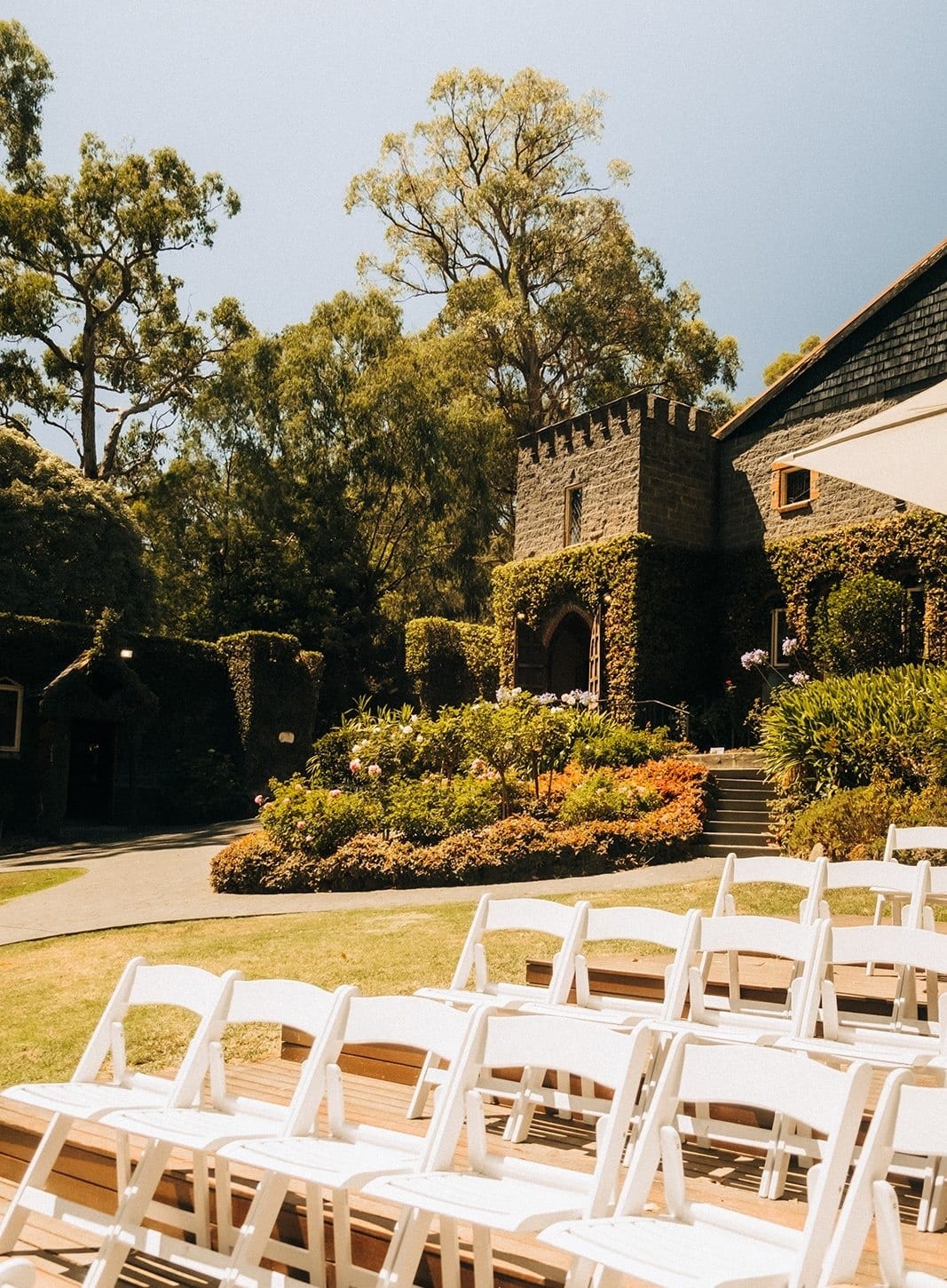 Rows of white folding chairs on the timber ceremony deck, the ivy-covered castle beyond