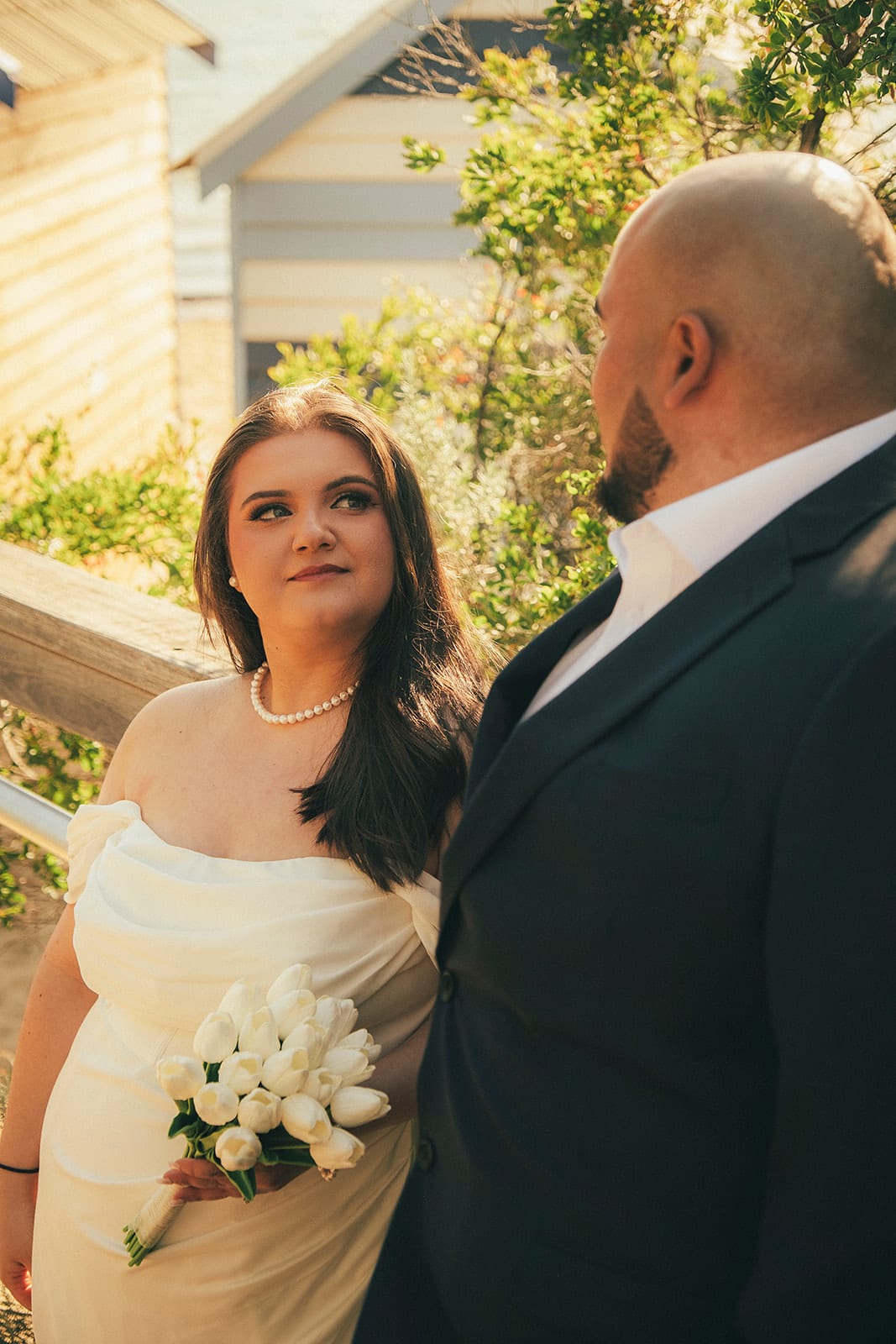 Martina smiling up at Diego beside a white bathing box and its timber rail