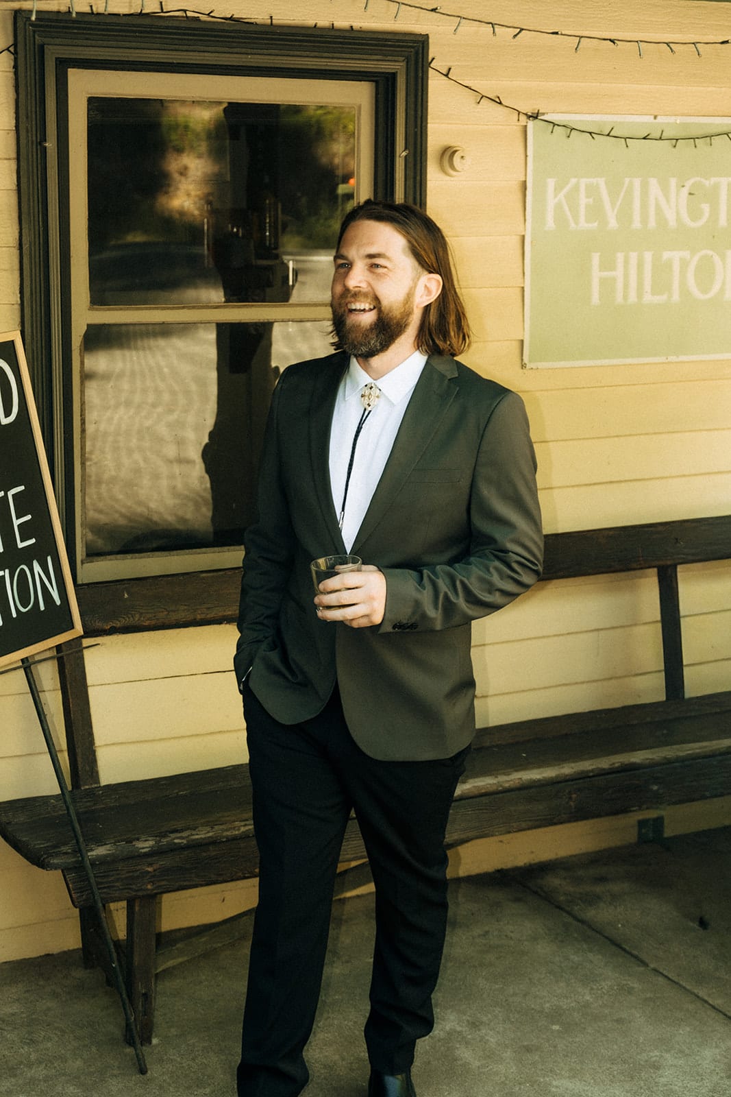 Todd on the timber veranda beside a hand-painted Kevington Hilton sign