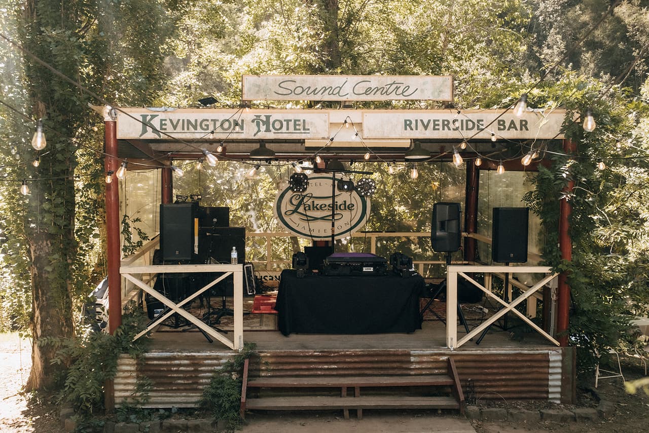 The hotel’s riverside stage under a Sound Centre sign, festoon lights strung across it and speakers set up