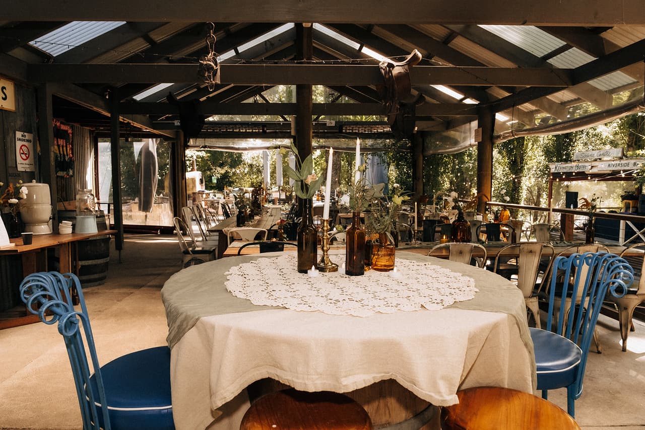 The bridal table under the pavilion, a round table with a lace doily, candles and blue bentwood chairs