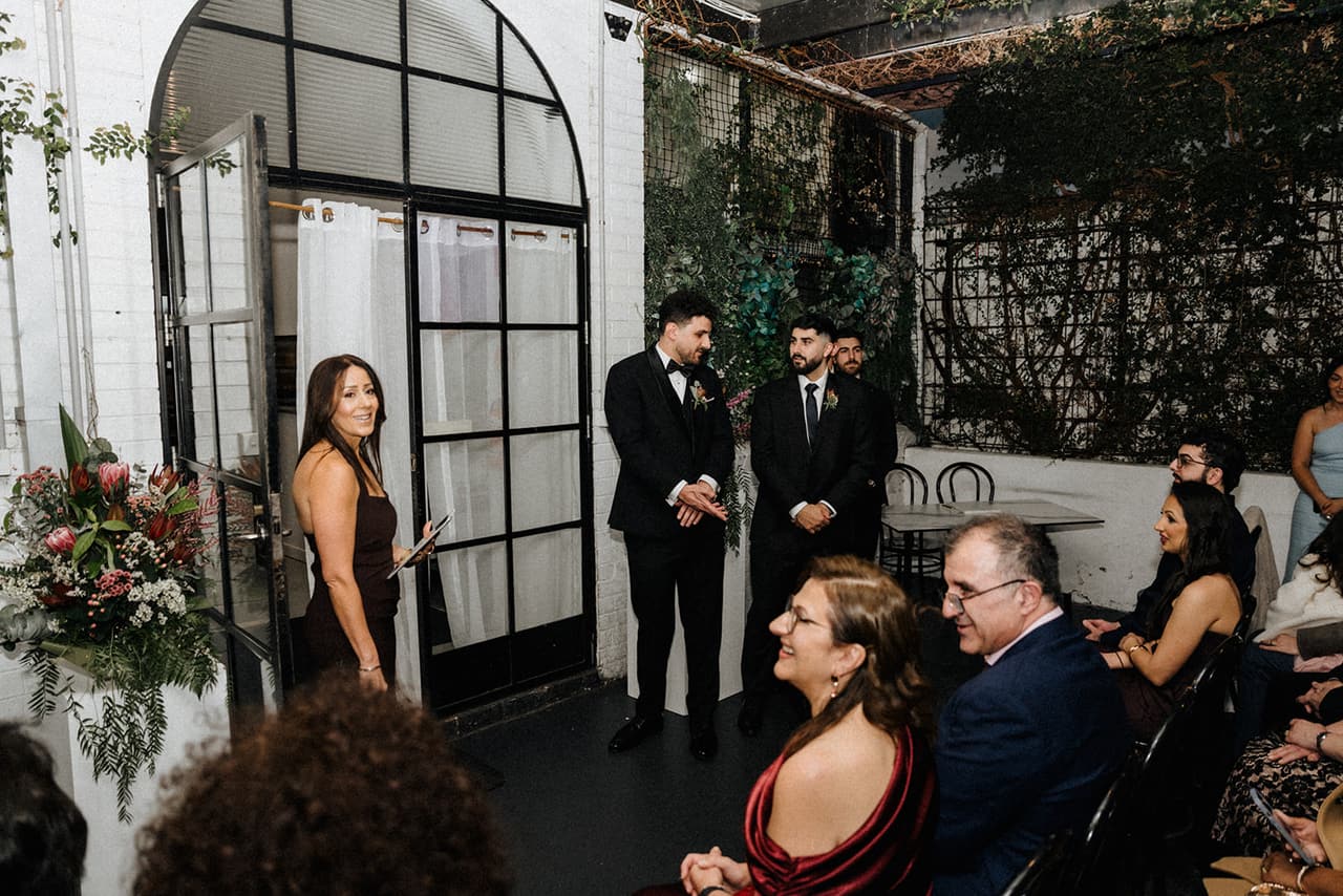 The front of the covered courtyard before the ceremony, with its tall arched black window, white brick walls and flowers on a white plinth