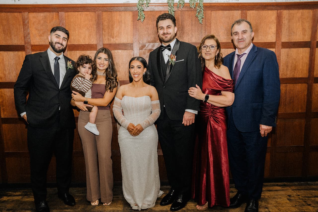 George and Tia with family in front of the timber panelling before the ceremony