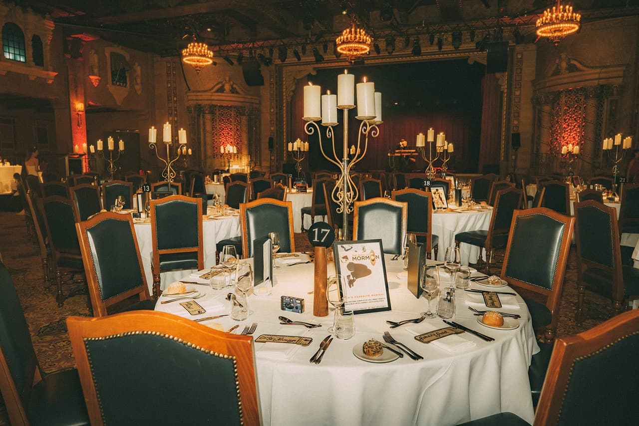 Candlelit round tables beneath the chandeliers of the Plaza Ballroom