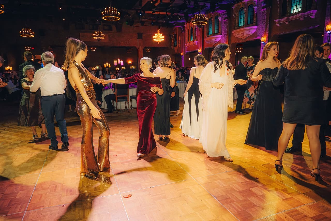 Guests dancing on the parquet floor, Kira in her gold sequined jumpsuit