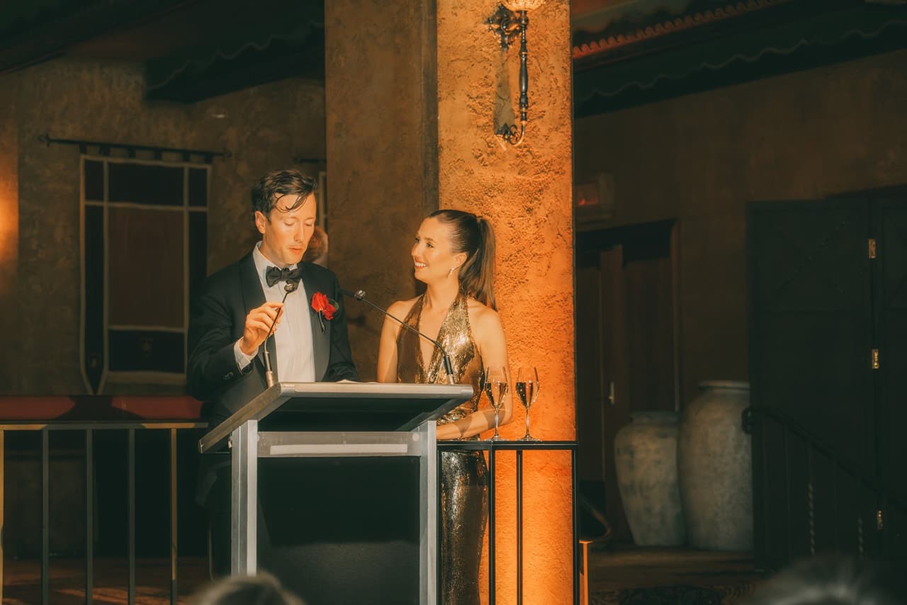 The MCs speaking at a lectern