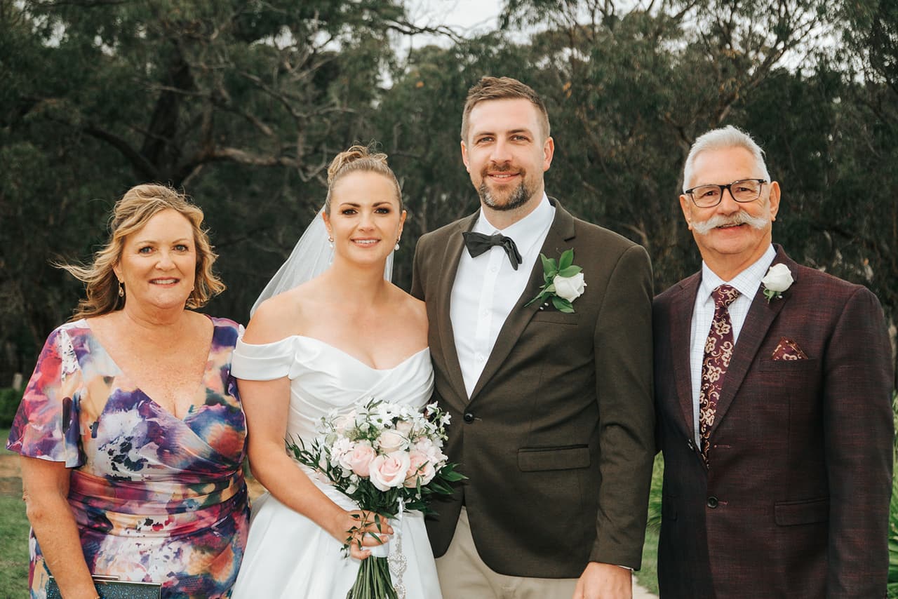 Jessica and Max with her mum and dad on the farm road, tall gums behind them