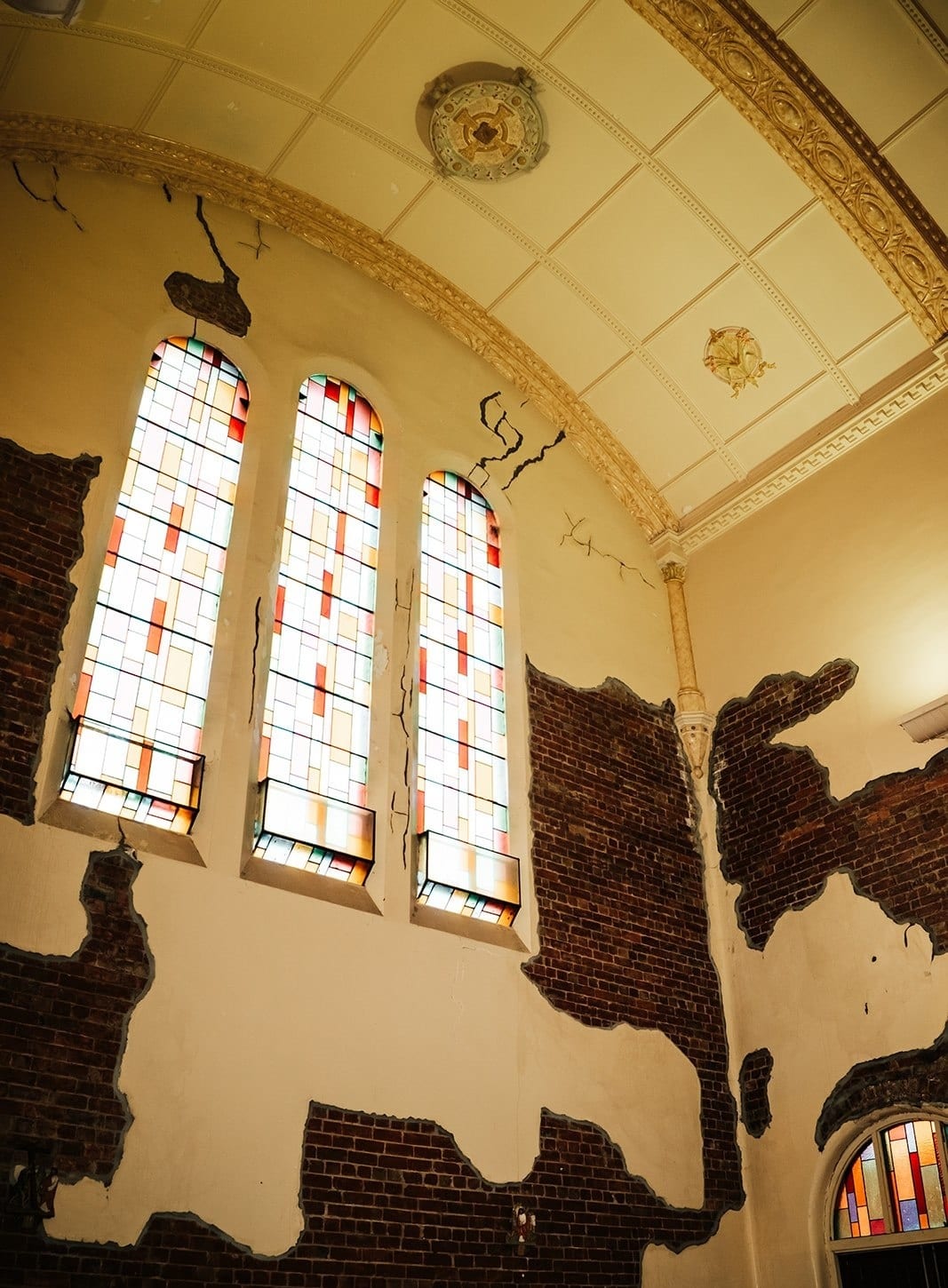 Three stained glass windows high in the plaster and brick wall