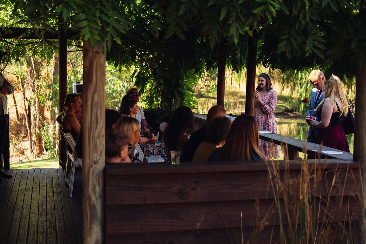 Guests seated under the vine-covered pergola of the Boatshed as the ceremony is about to begin