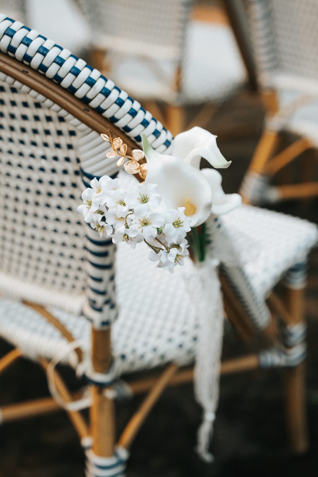 A white bow and pink flowers tied to the end of a ceremony chair