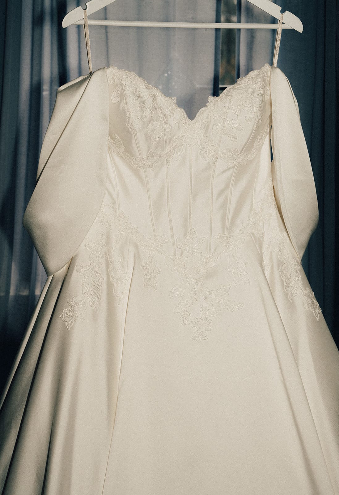 Porscha’s gown on its hanger against a white wall in the bridal room
