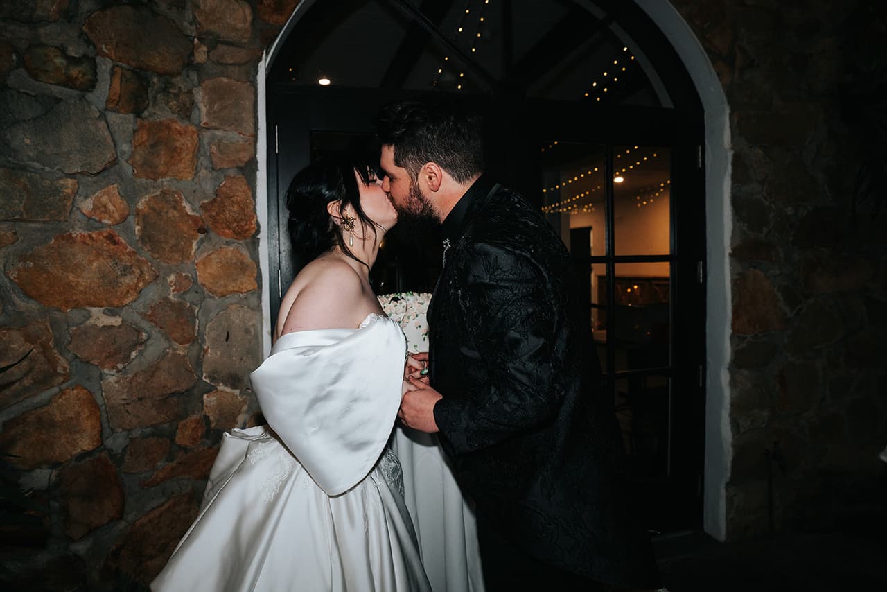 Porscha and Jordan kissing in a stone archway during the reception