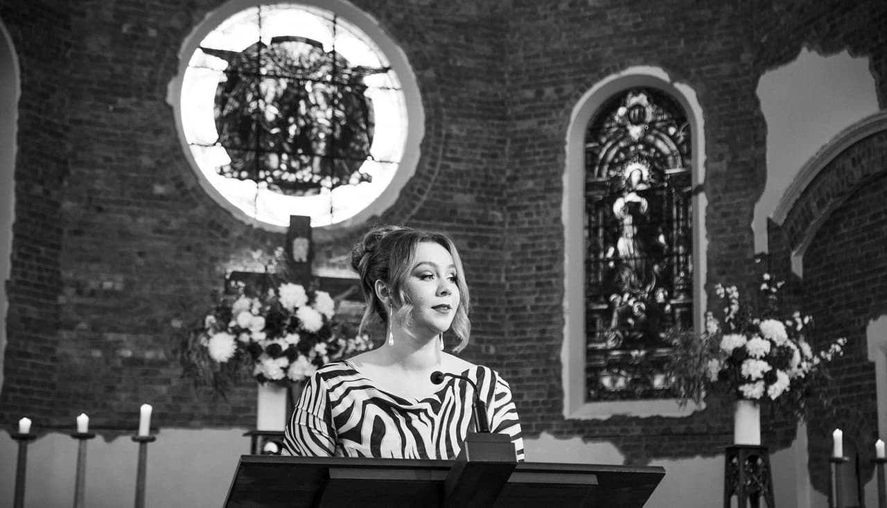 Black and white photo of a guest in a zebra print dress reading at the lectern