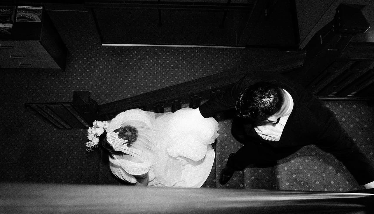 Black and white photo from above of Bryan helping Ashley down the timber staircase