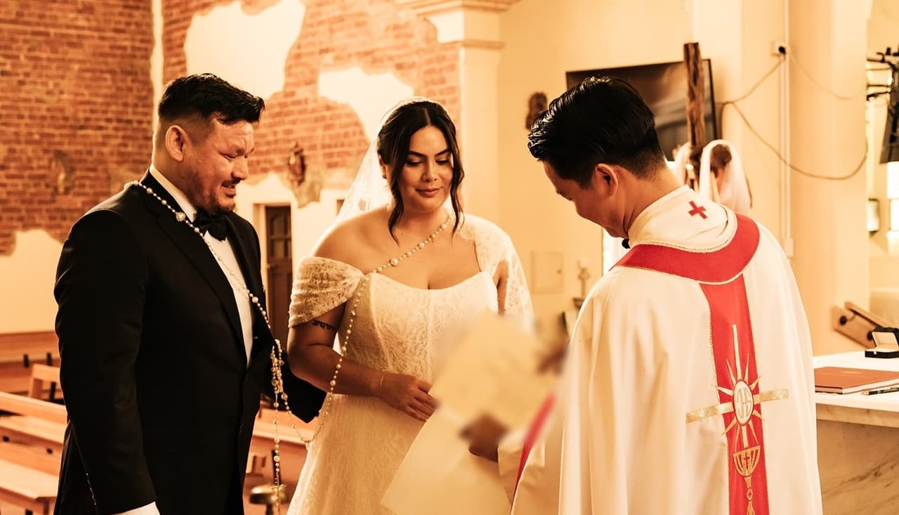 The priest presenting Ashley and Bryan with their marriage certificate