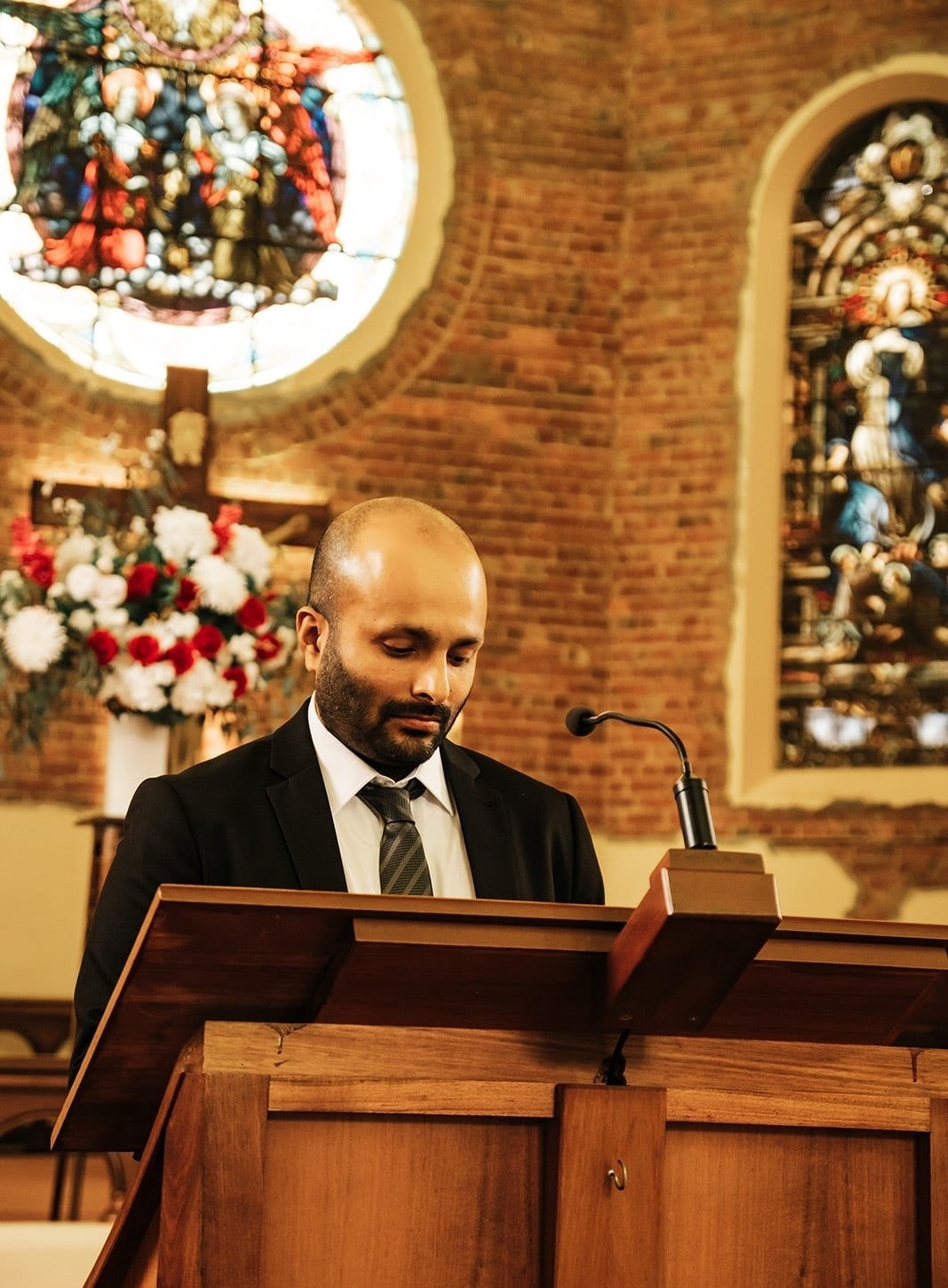 A guest reading at the lectern beneath the stained glass windows