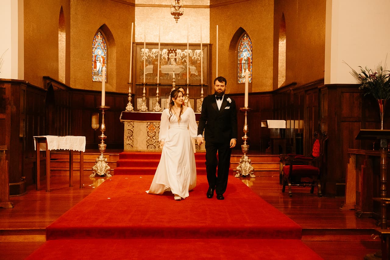 Bianca and Aidan starting down the red carpeted steps from the altar at the end of the ceremony