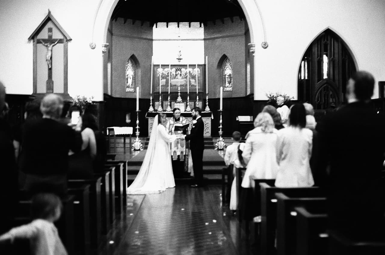 Black and white photo of the ceremony inside St Peter's Eastern Hill, seen from the back of the church, on 35mm film