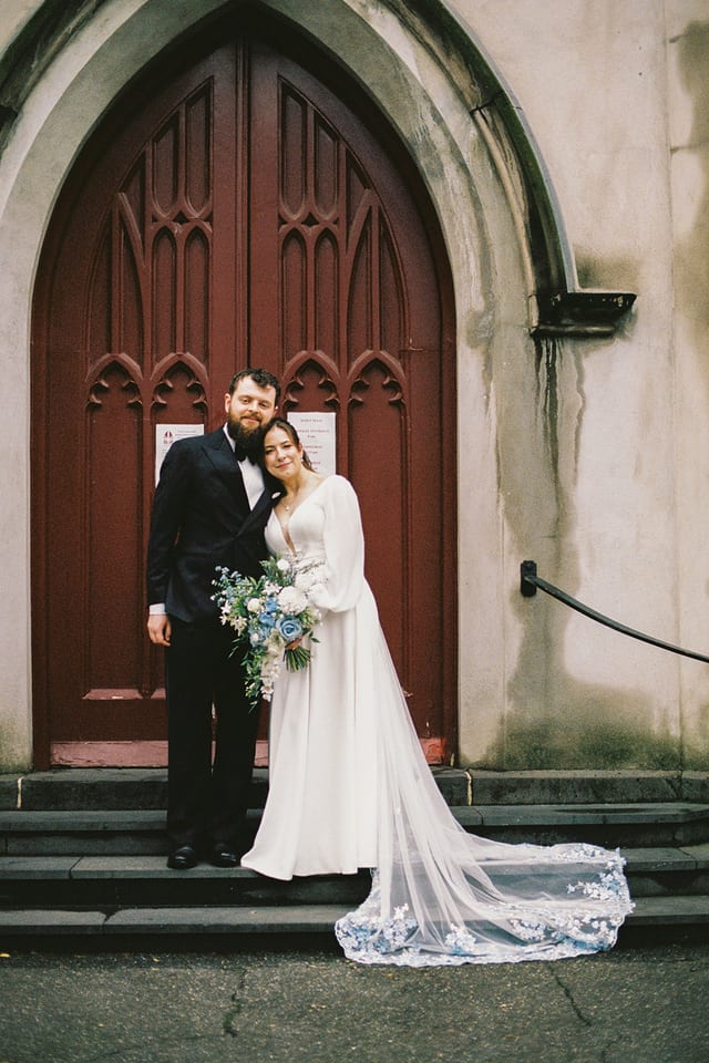 Bianca and Aidan on the steps at the church's arched wooden door, on 35mm film