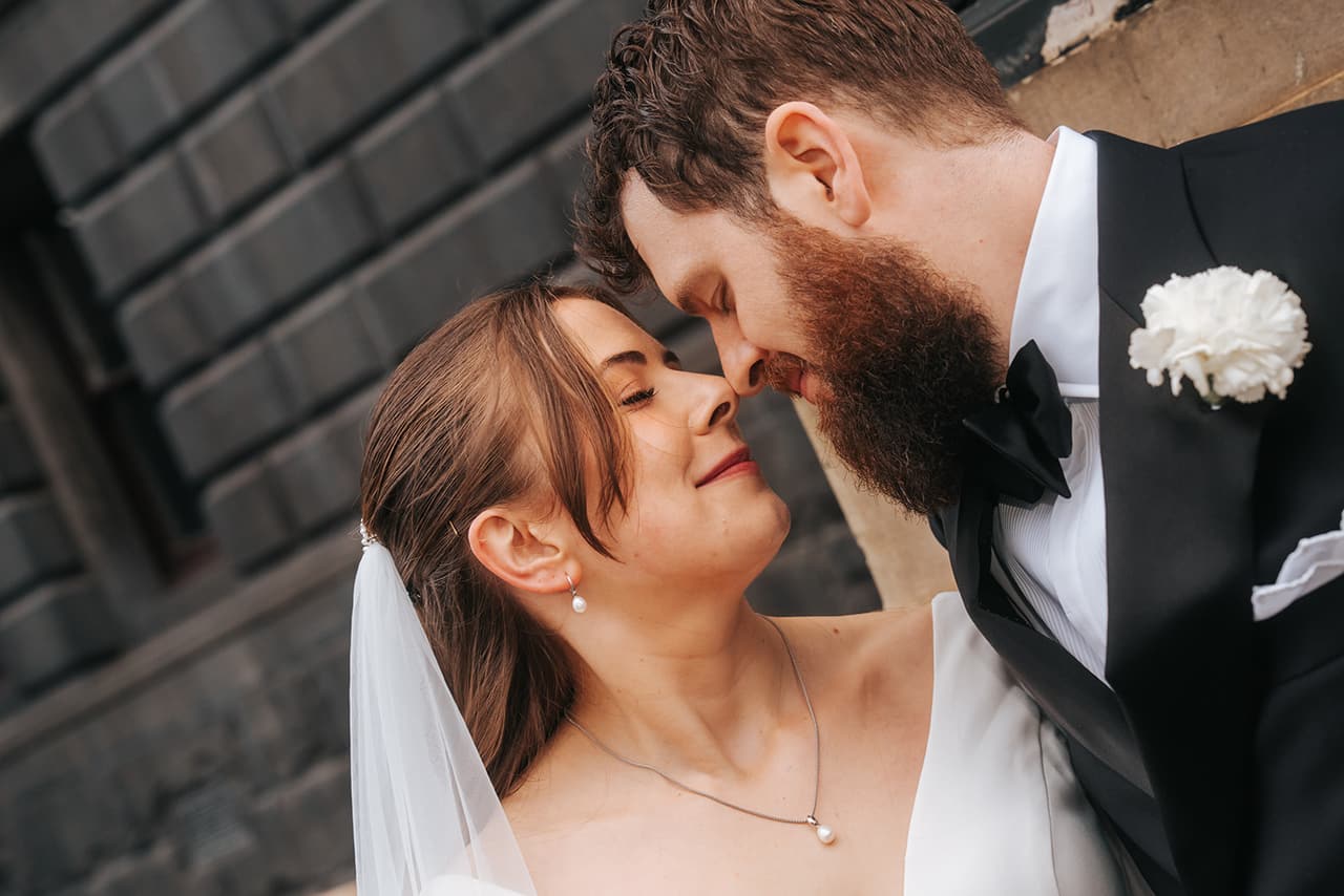 A close portrait of Bianca smiling up as Aidan leans in, nose to nose