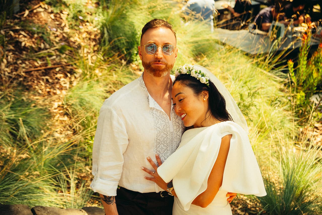 Cecile resting against Stefan’s chest among the long grass by the river