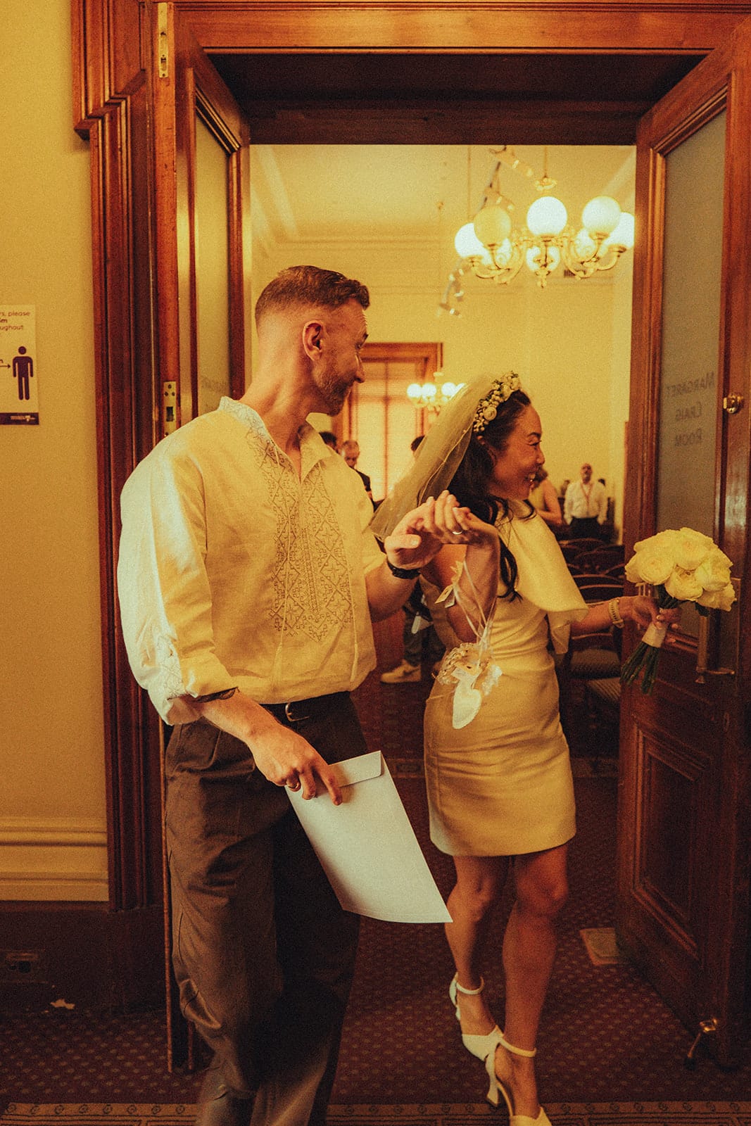 Cecile and Stefan stepping out through the timber doors of the Margaret Craig Room hand in hand