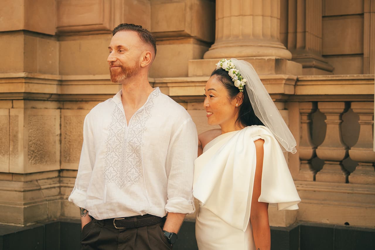 Cecile and Stefan smiling side by side against the sandstone columns and balustrade of the Old Treasury Building