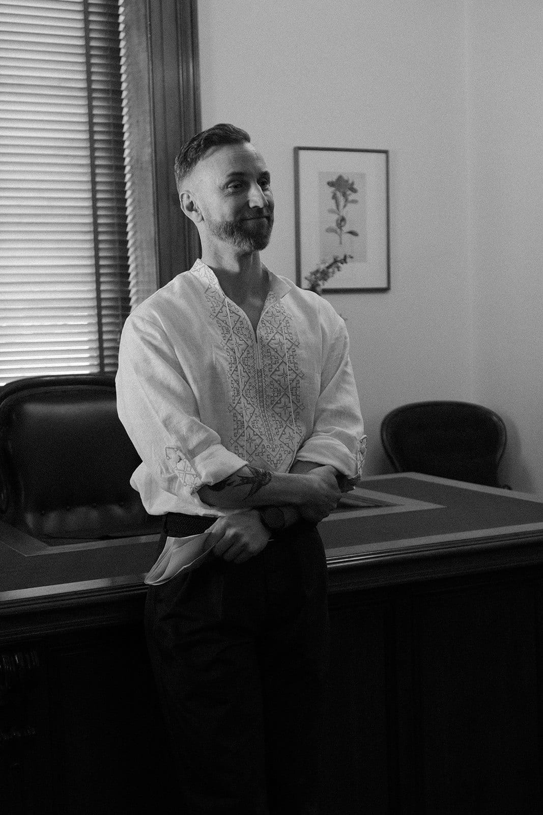 Black and white photo of Stefan leaning on the registry desk and smiling as the ceremony begins