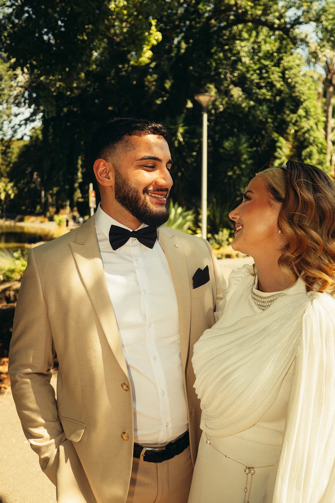 Yasir grinning as Elektra looks up at him under the trees