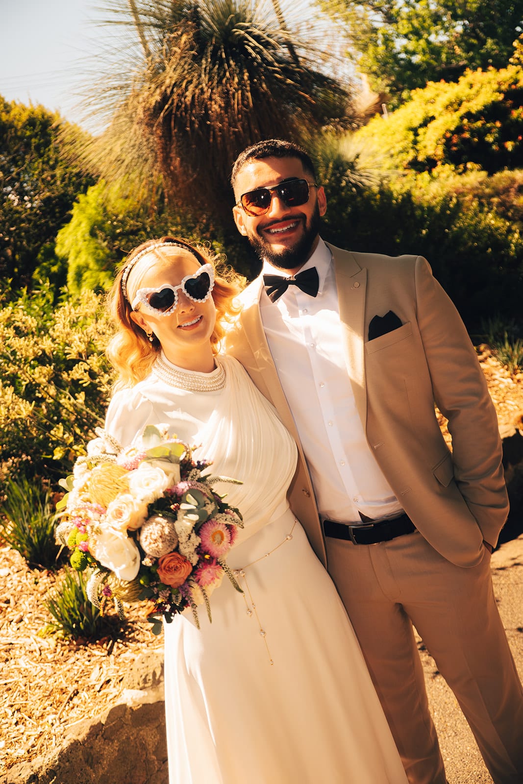 Elektra in white heart-shaped sunglasses smiling beside Yasir in his sunglasses