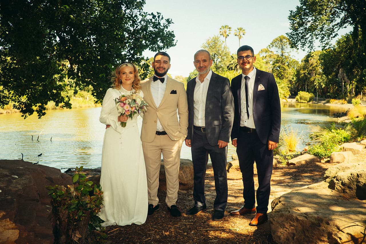 Elektra and Yasir with two guests in dark suits beside the lake