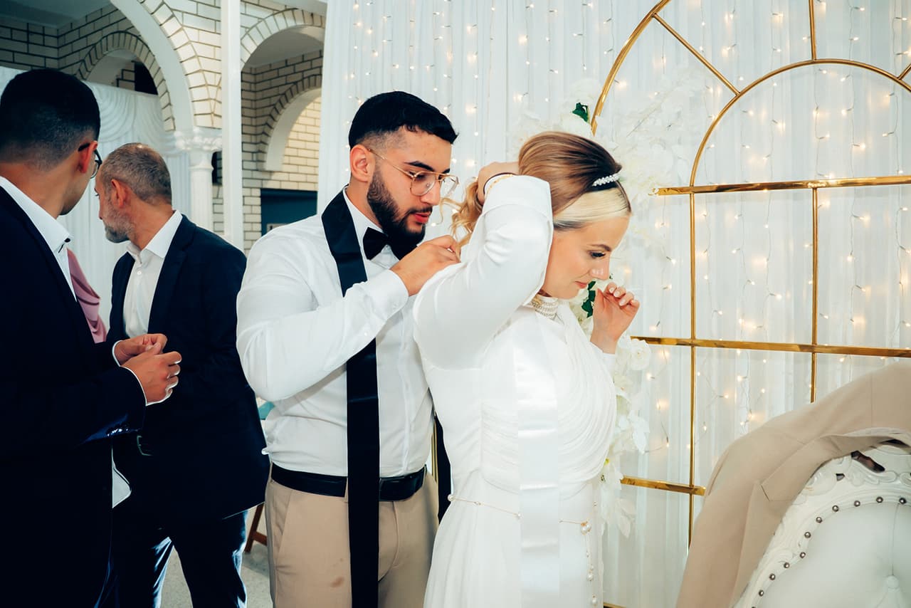 Yasir fastening a necklace for Elektra as she lifts her hair