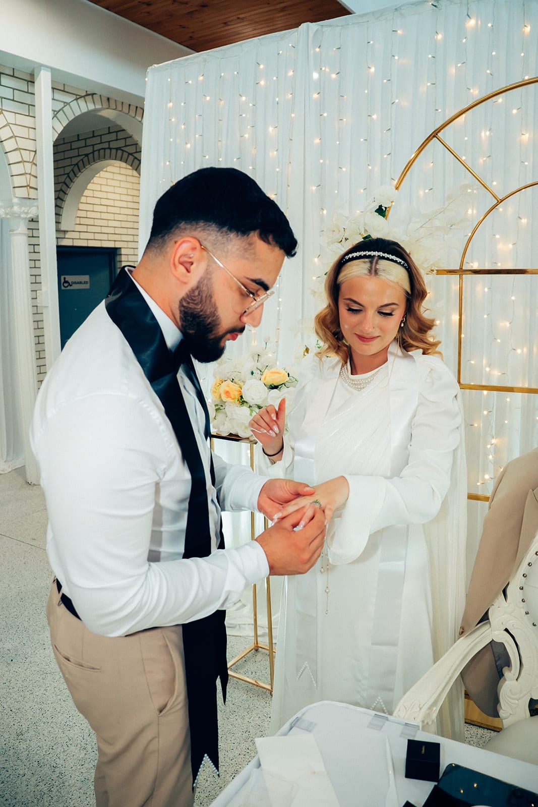 Yasir sliding a ring onto Elektra’s finger in front of the gold arches