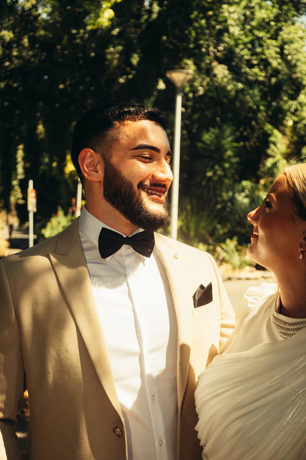 Yasir laughing in a cream suit and black bow tie