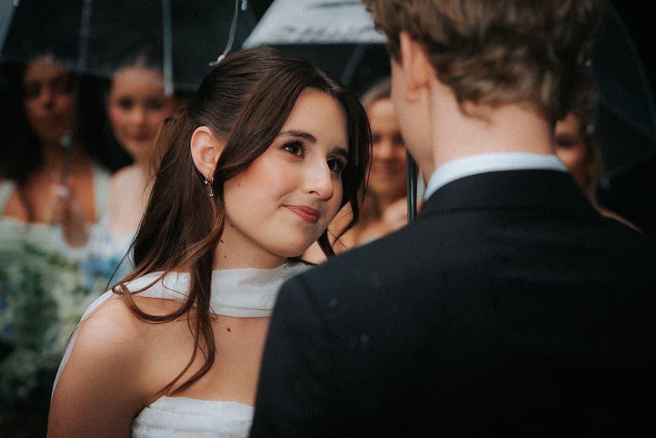 Charlotte smiling up at Eli during the ceremony, bridesmaids behind her