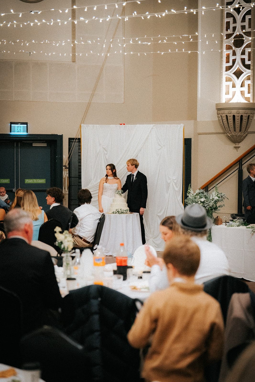 Guests at round tables watching the cake cutting at Woodville Town Hall