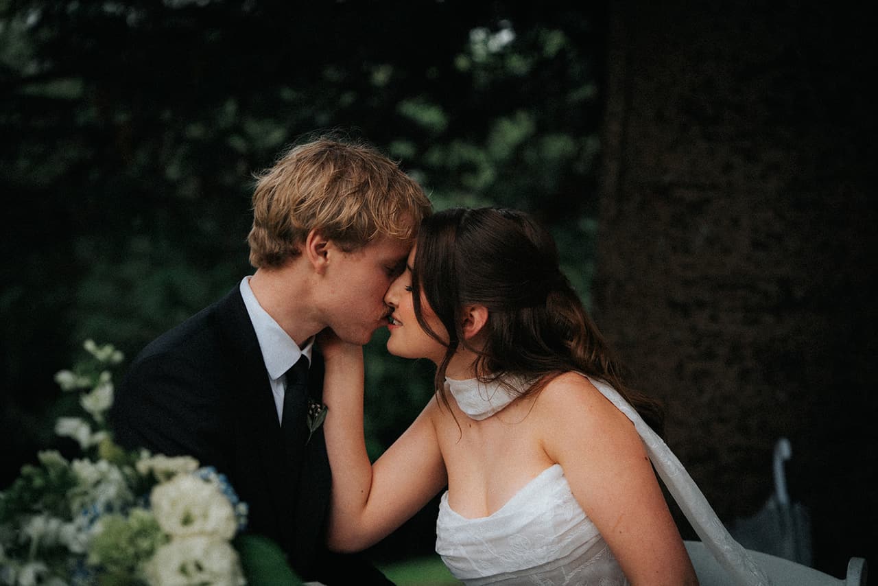 Eli and Charlotte kissing at the signing table, her hand on his cheek