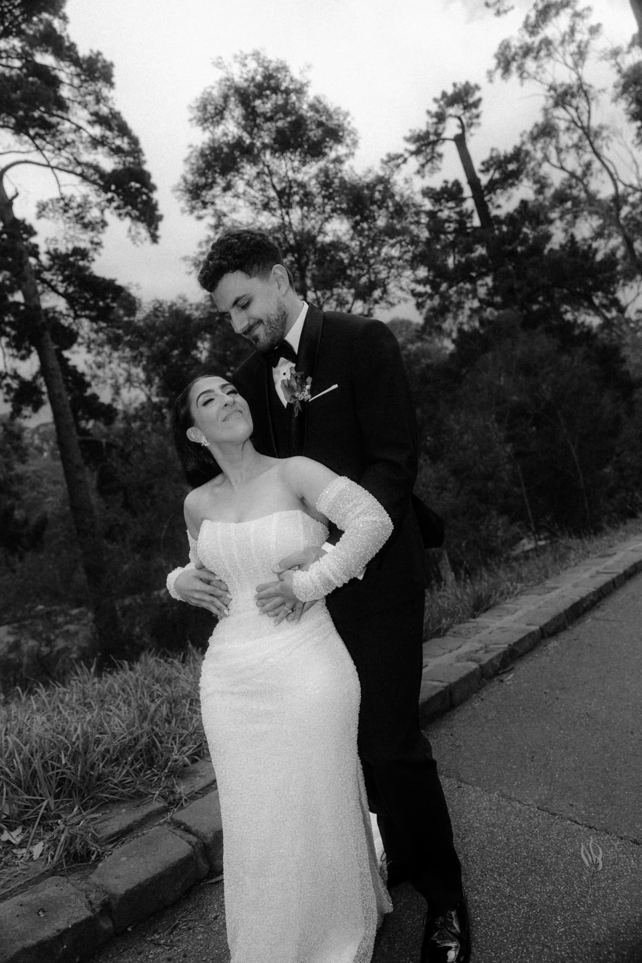 Black and white photo of George holding Tia from behind as she leans back laughing