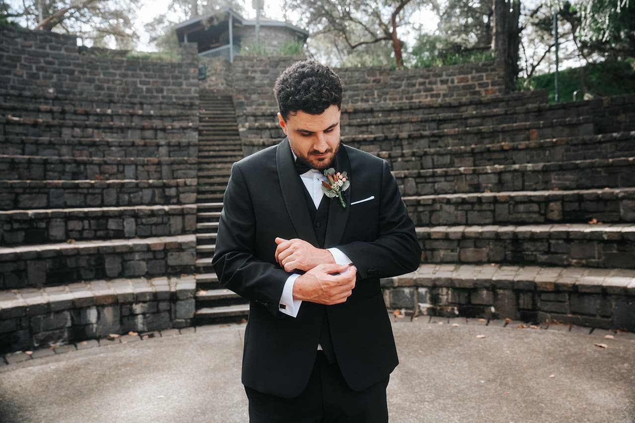 George adjusting his cuffs as he waits alone in the stone amphitheatre