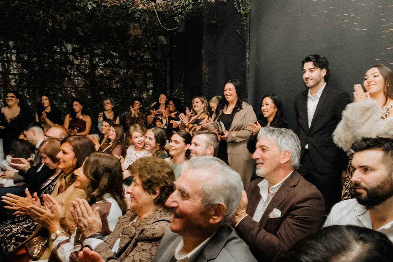 Guests clapping and smiling from their seats during the ceremony