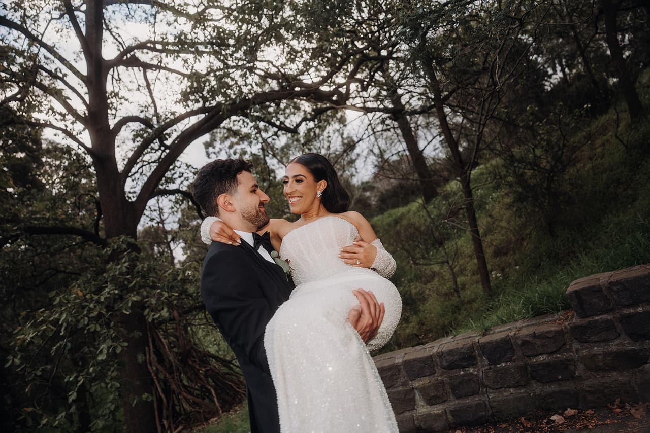 George lifting Tia off her feet as they both laugh under the trees