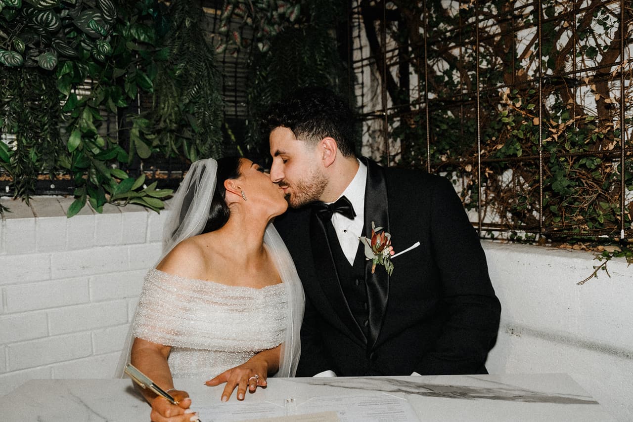 George kissing Tia at the signing table