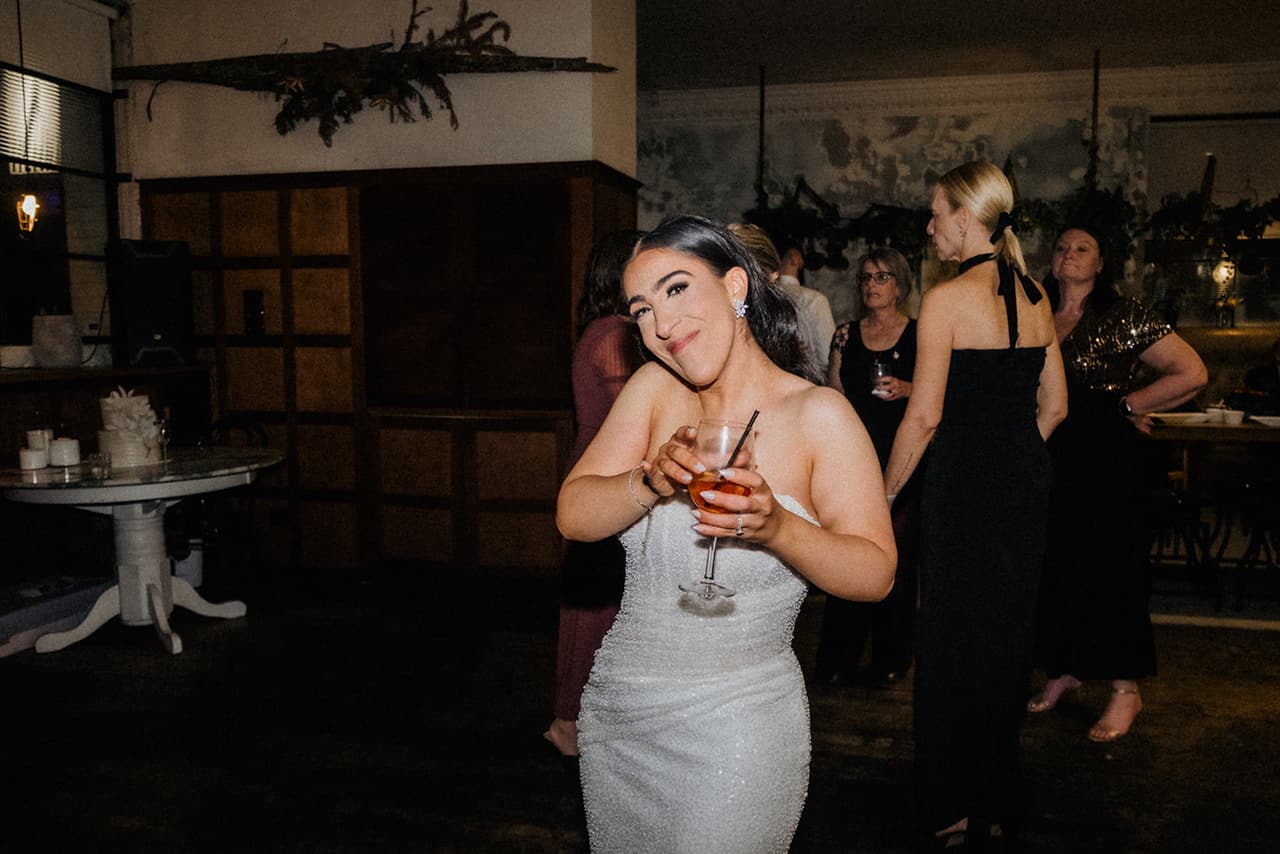 Tia dancing with a drink in her hand on the dark dance floor