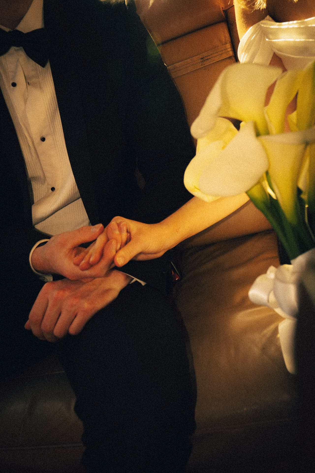 Josh holding Hannah’s hand in the back seat, calla lilies resting on her lap