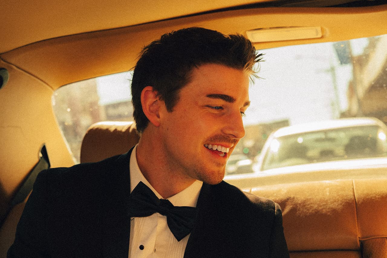 Josh smiling at Hannah in the back seat, the street through the rear window behind him